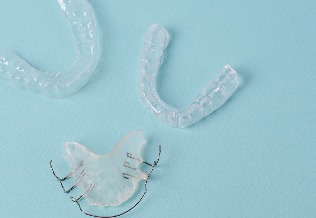 Stock image of two clear aligners and one metal retainer